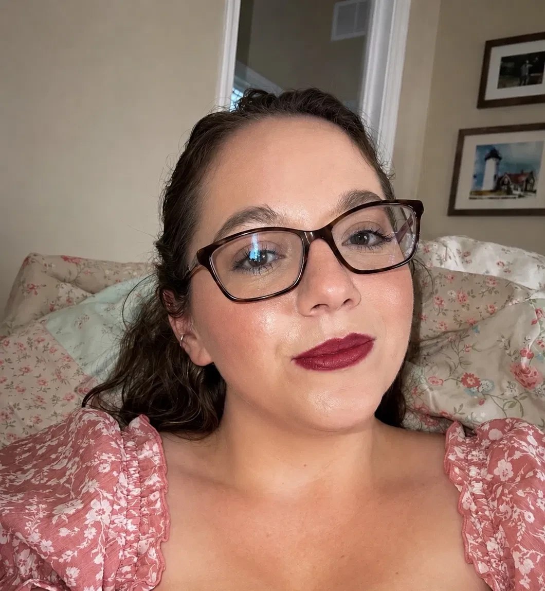 The maker behind Dragon Ink and Thread, smiling in a pink floral top