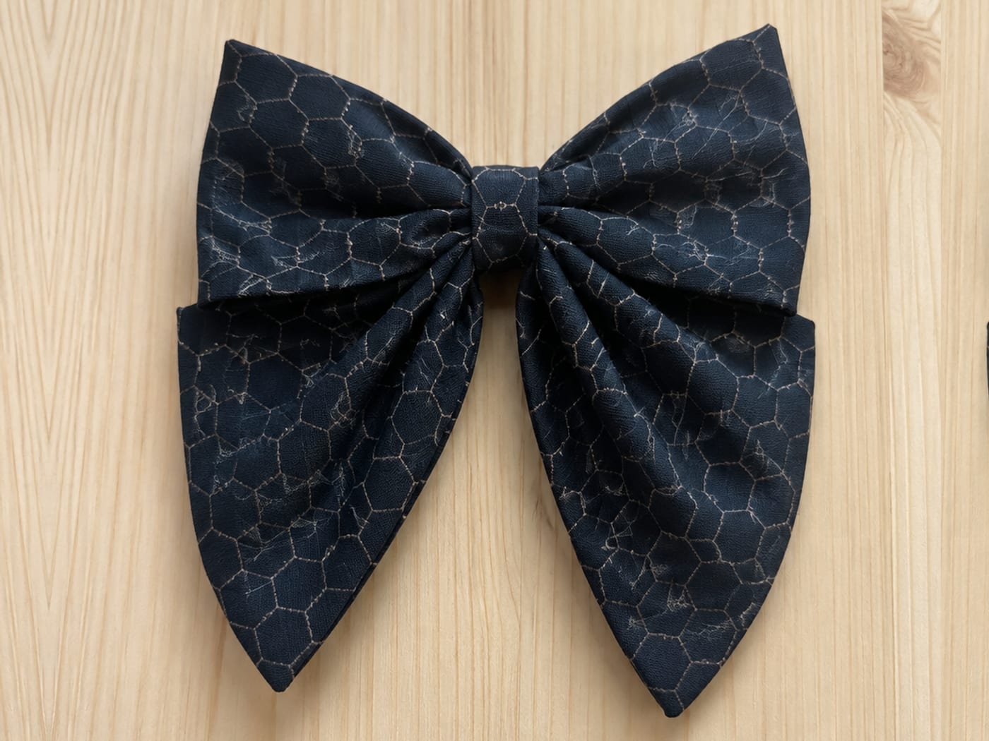 Handmade midnight-navy sailor bow with a fine bronze crackle-web texture