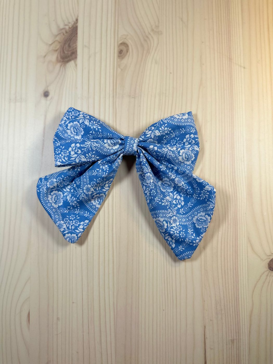 Handmade sailor bow in mid-blue cotton covered with white lace medallions and scalloped bands