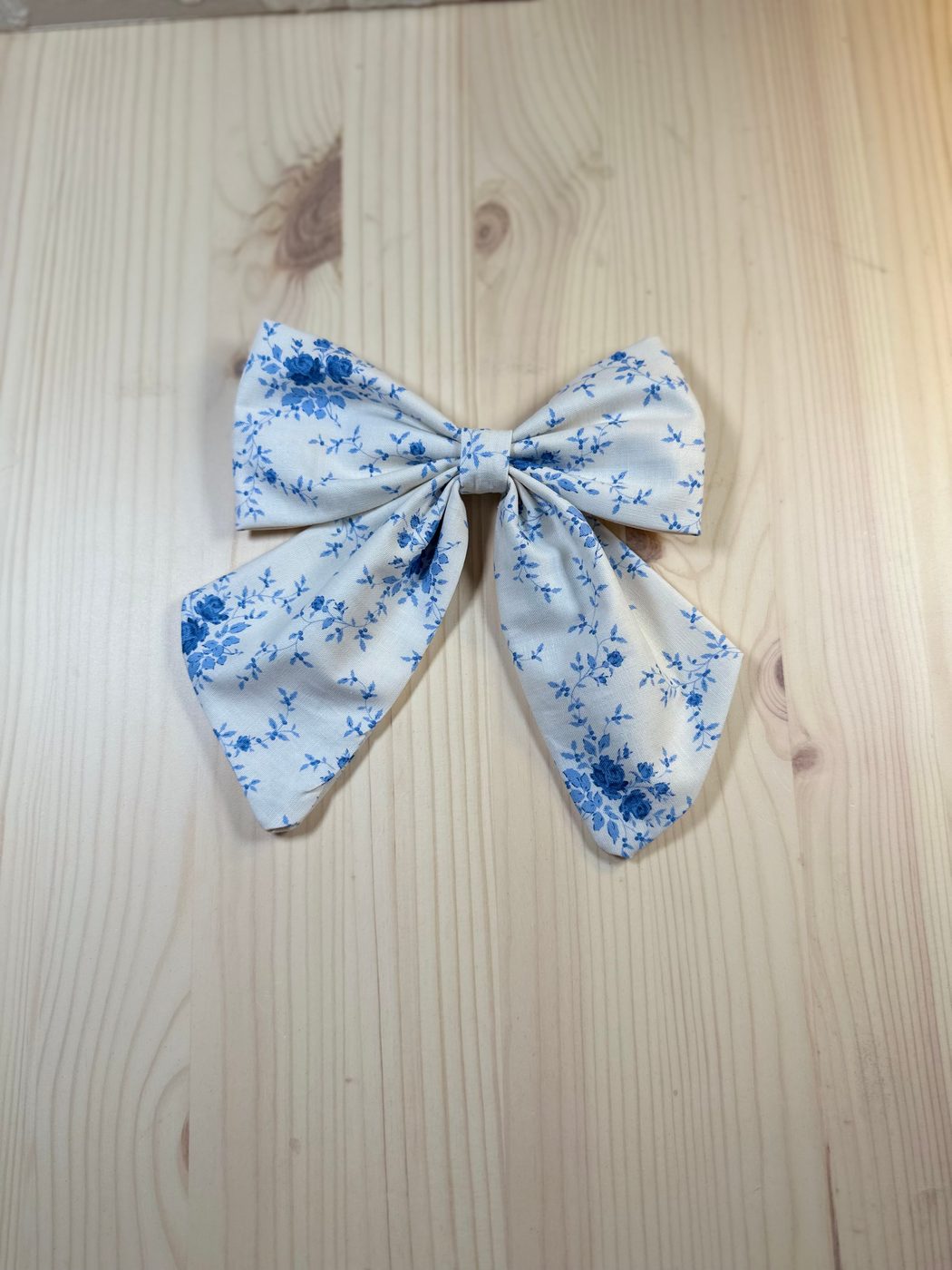 Handmade sailor bow in cream cotton scattered with small blue roses and sprigs