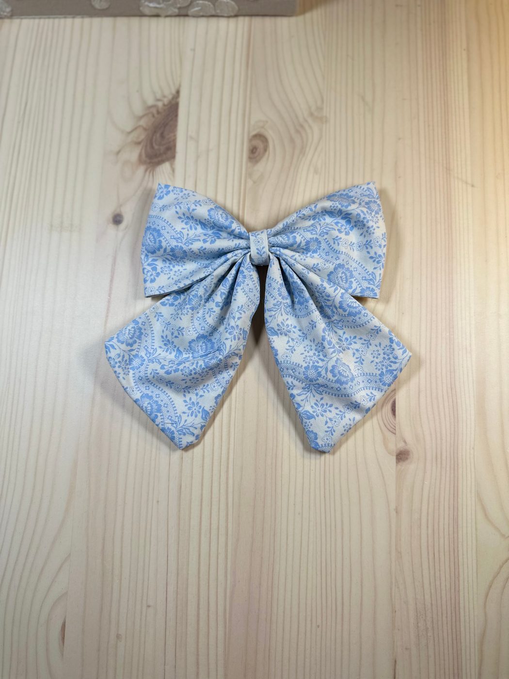 Handmade sailor bow in pale blue cotton with a fine white-and-blue lace floral pattern
