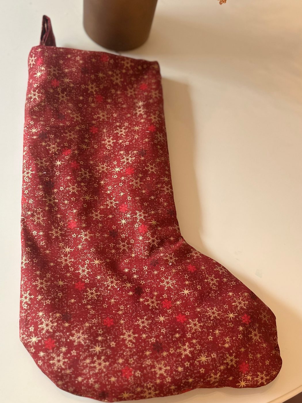 The same stocking laid flat on a pale table, showing its full shape and the shaped foot