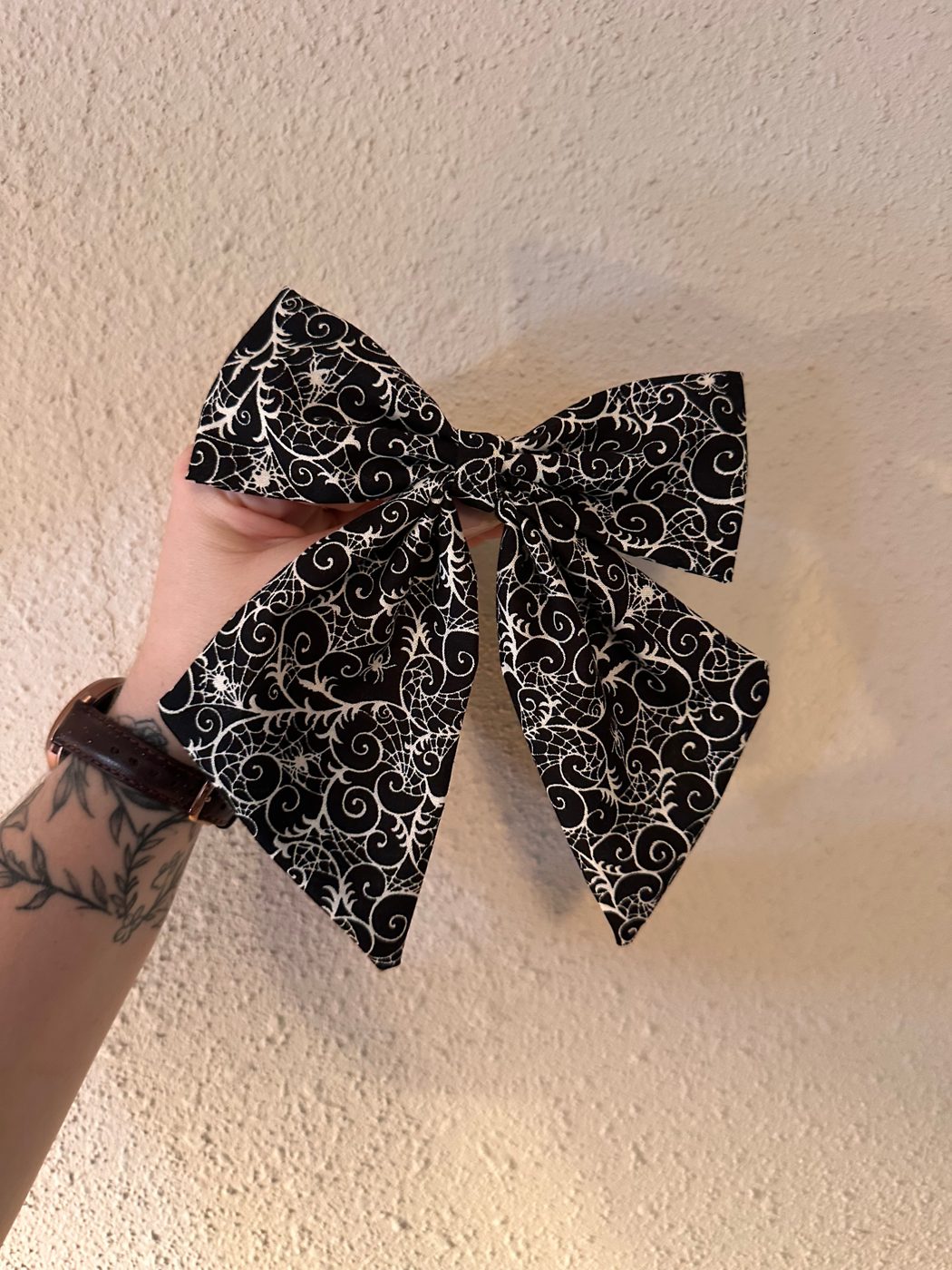 The finished sailor bow in a black and white spider-web print, held up against a wall