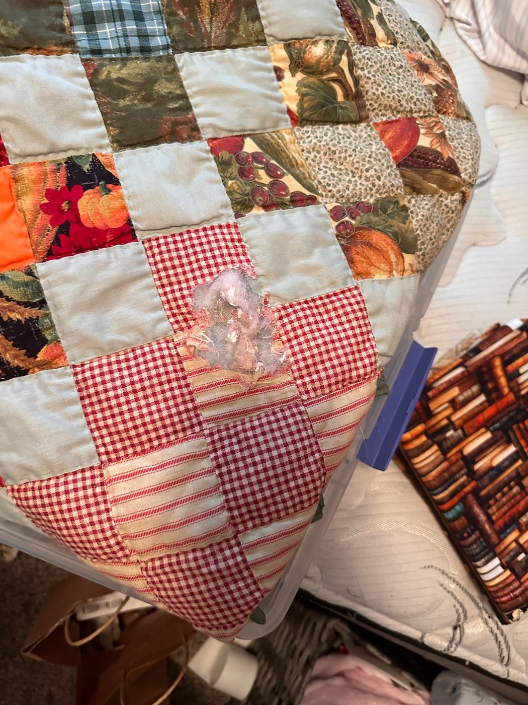 A hole worn clean through a patchwork quilt where four seams meet, with the batting coming out